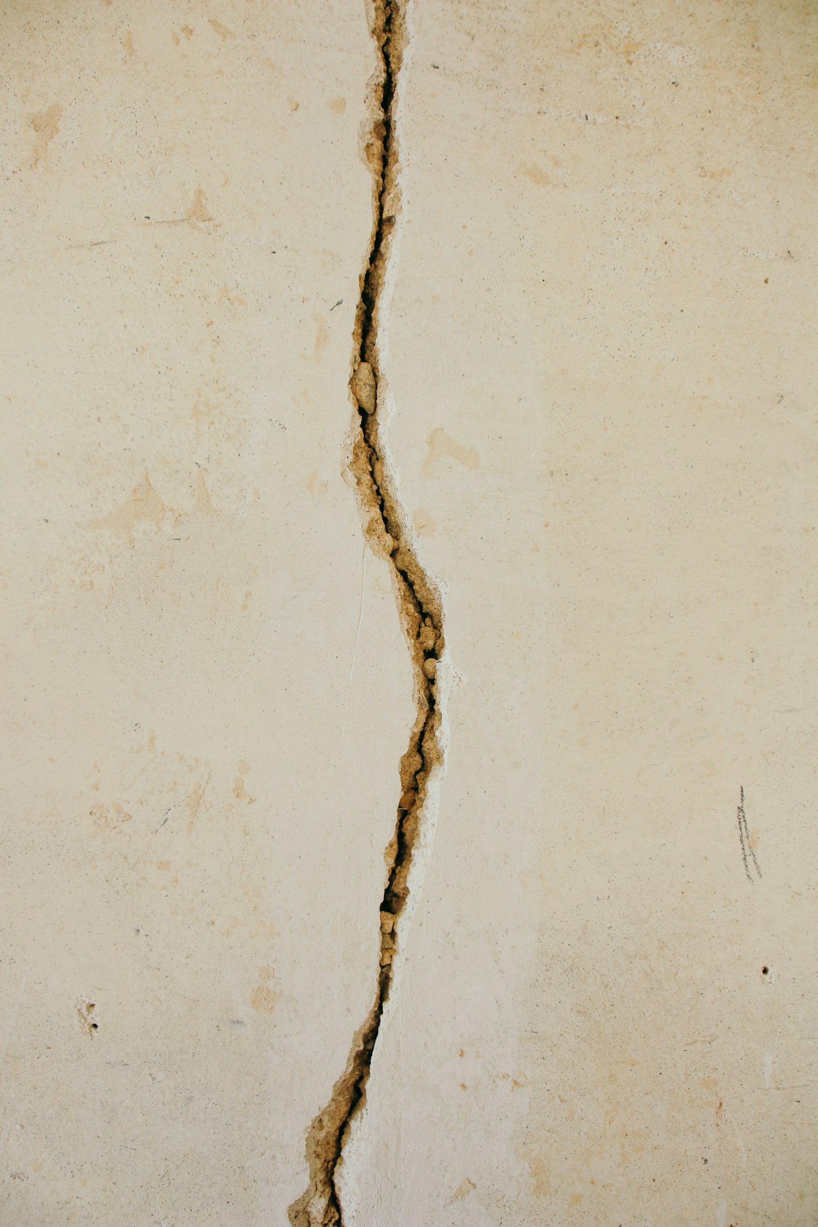 Vertical crack running through a white concrete wall